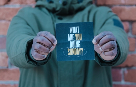 Man Holding Sign Saying "What Are You Doing Sunday?"